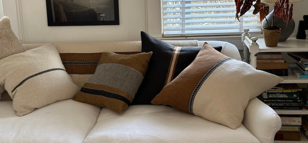 a pile of linen Libeco pillows in shade sofa brown, black on a cream linen sofa