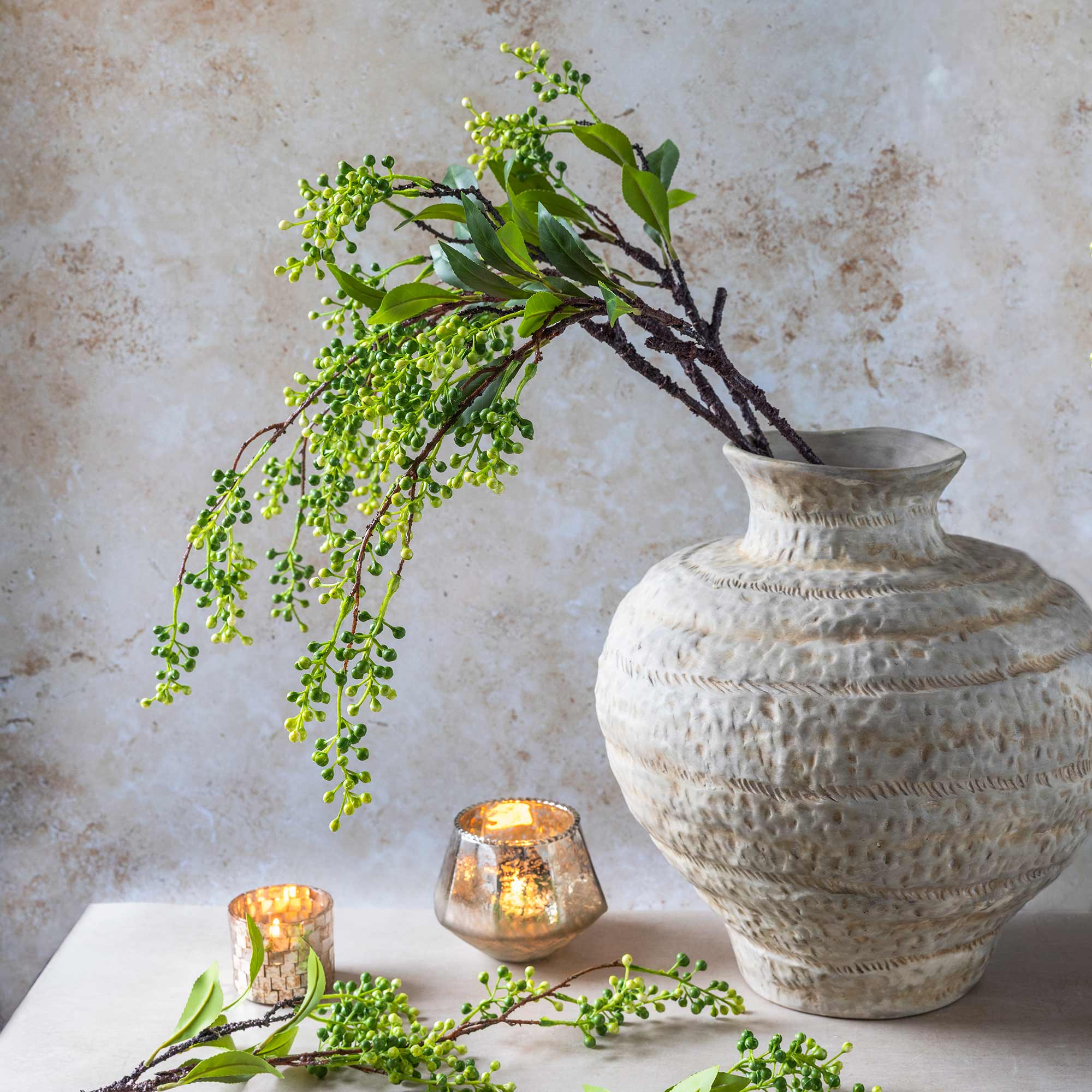 Faux viburnum branch with trailing green berries in a ceramic vase