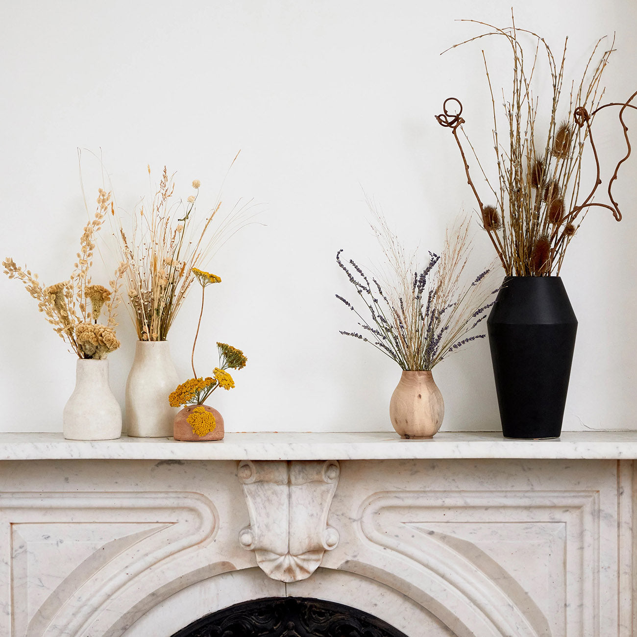 Terra cotta frog vases on a mantel with dried botanicals