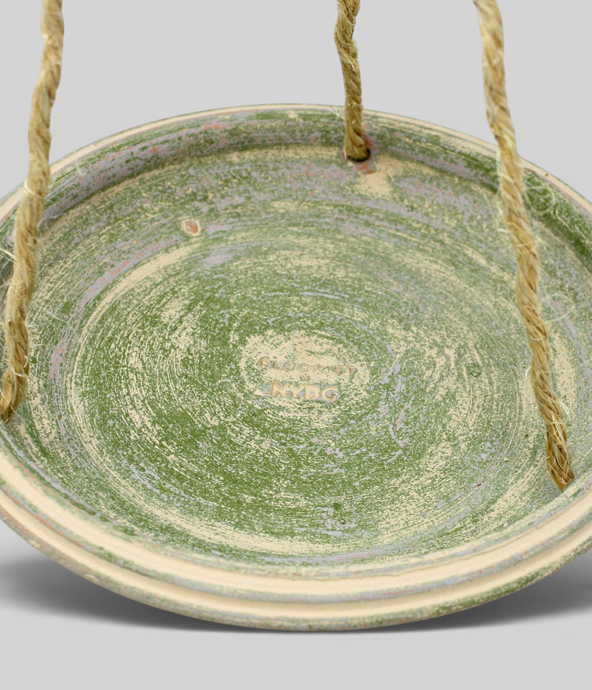 Close-up of the Garden Sage terracotta bird bath suspended by three jute cords, with Bloomist x NYBG branding visible inside the basin