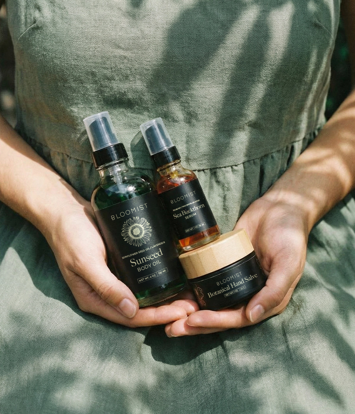 Hands holding a jar of botanical hand salve, sunseed body oil and sea bucktorn serum