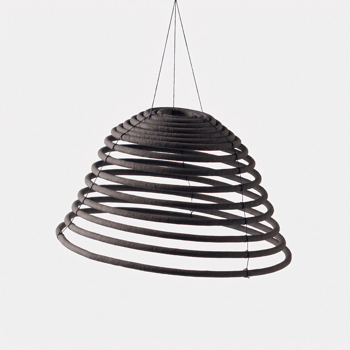 Black citronella incense coil suspended by hanging thread 