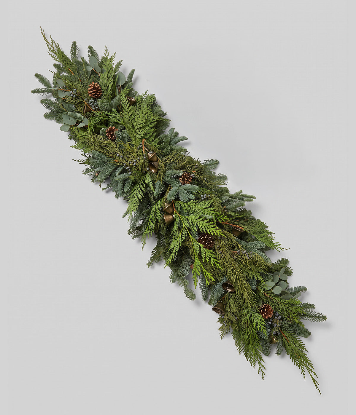 Clara juniper garland with fresh evergreens, blue berries, pine cones, and antique-style bells