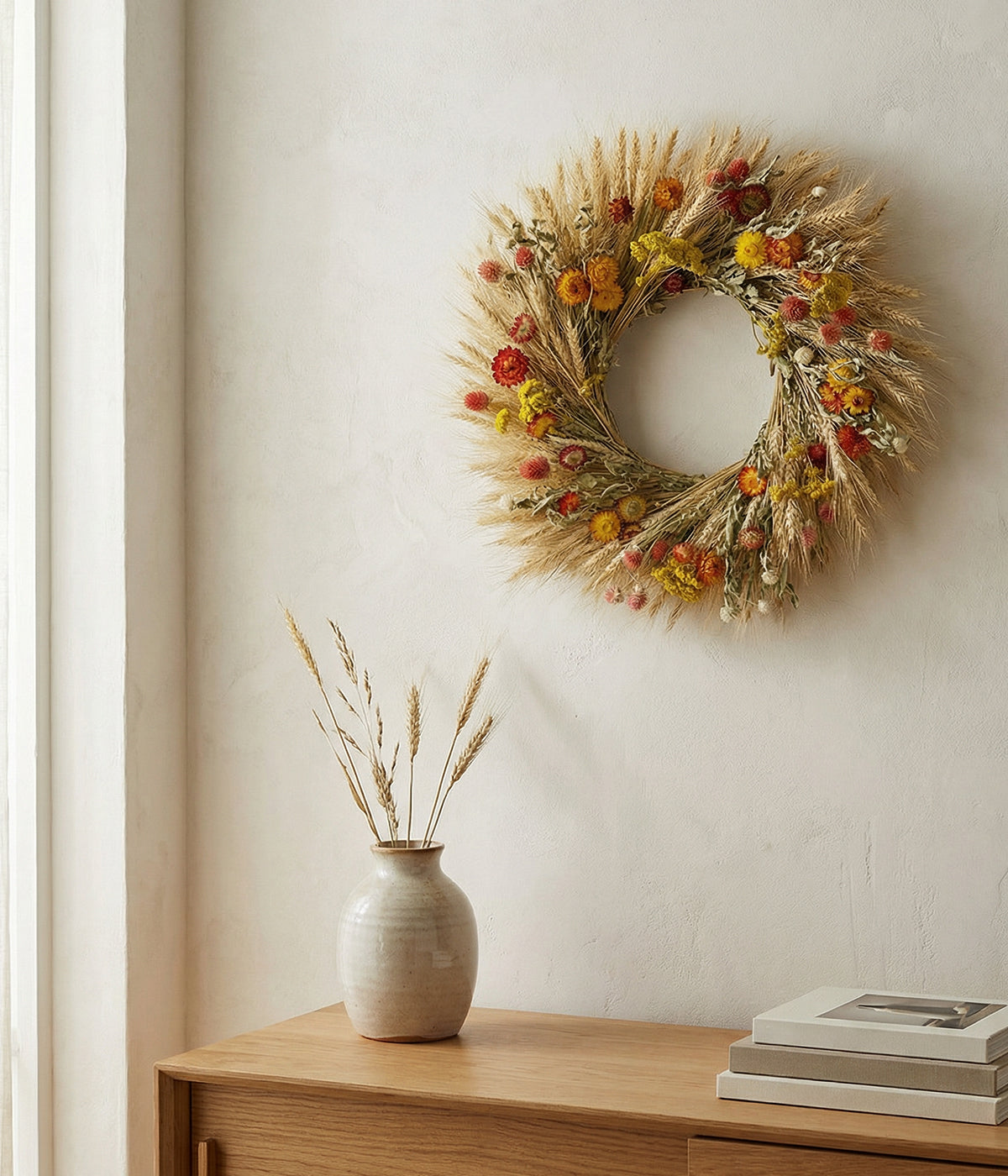 Louisa yellow wreath displayed on neutral wall above wooden console with pottery
