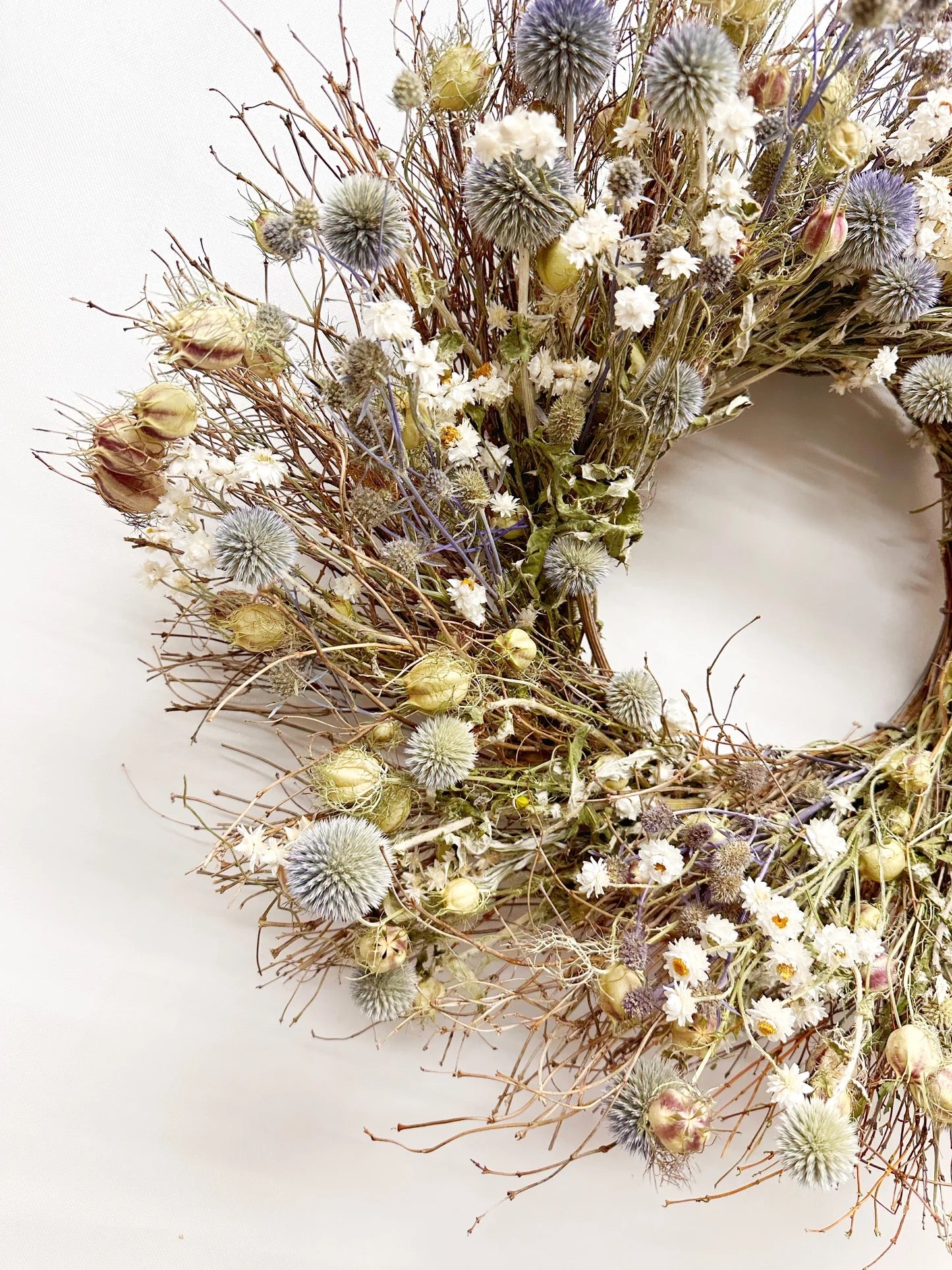Close-up of dried echinops thistle, ammobium daisies, and natural twigs in Rosalind wreath