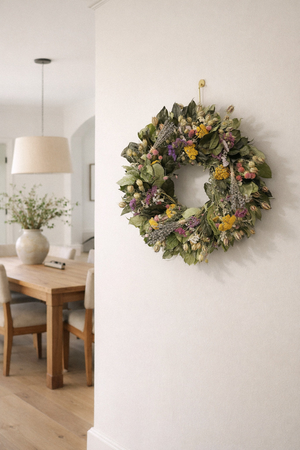 Preserved and dried spring wreaths hanging on a light plaster wall