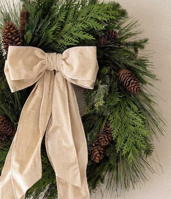Close-up of Eleanor fresh pine wreath with ivory velvet bow, mixed evergreen foliage, and natural spruce pine cones
