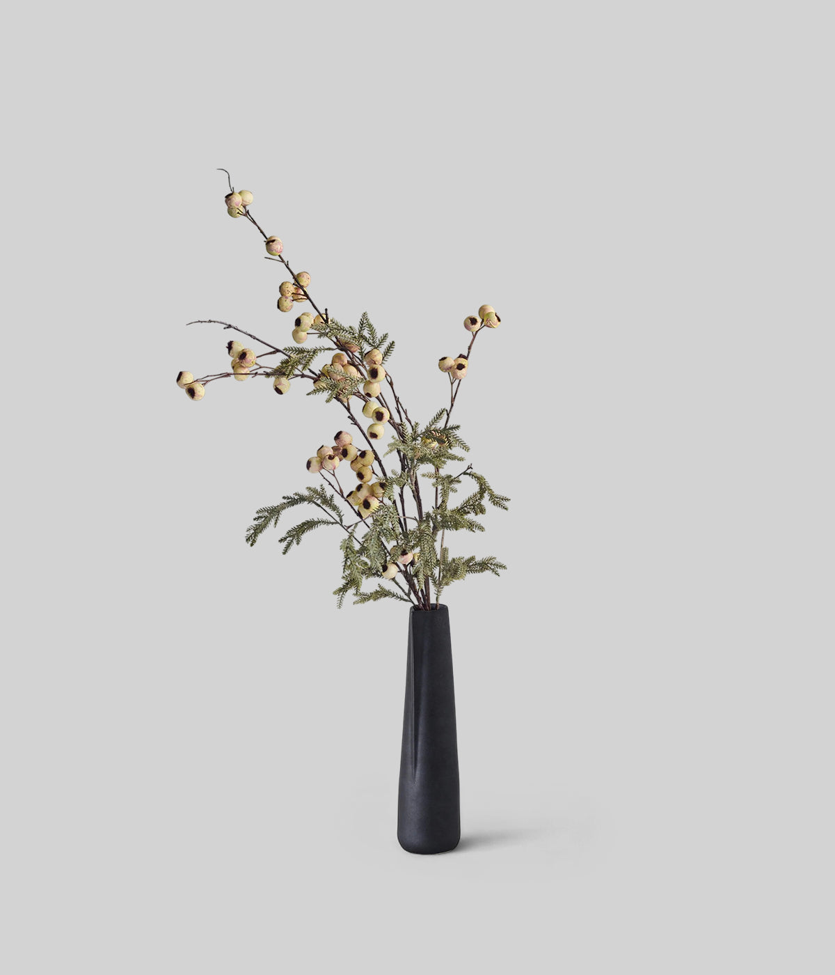 Winter botanical decor featuring faux hawthorn and pine stems in minimalist vase