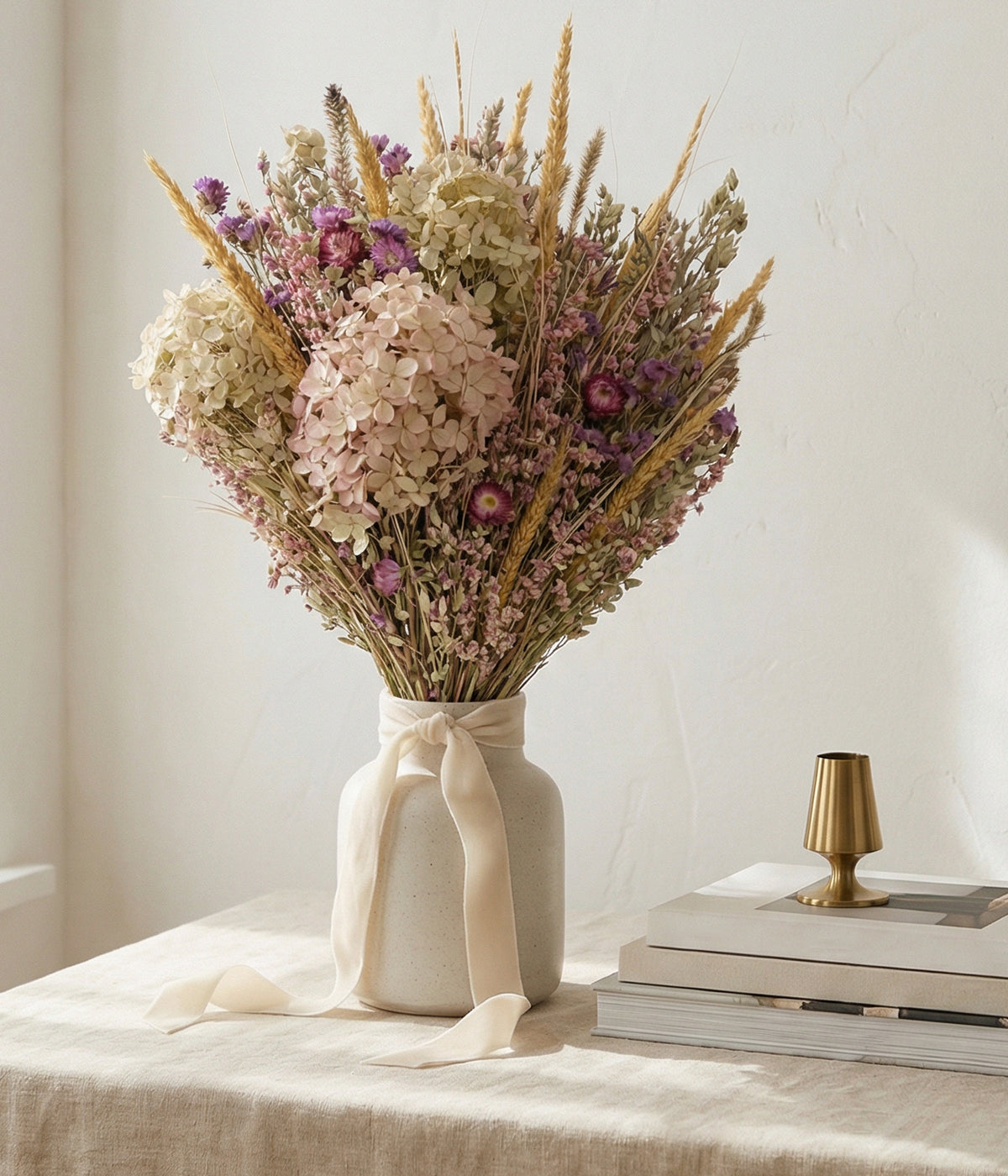 Dry flower arrangements with soft green and blush tones styled in a wide ceramic vase