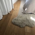 bamboo colored curly long wool sheepskin pelt on a bedroom floor with light casting across it
