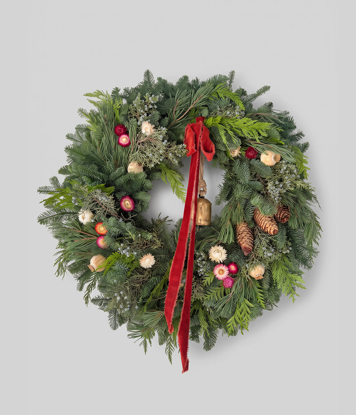 Juliette floral Christmas wreath with fresh evergreens, strawflowers, poppy pods, red velvet ribbon, and antique bell