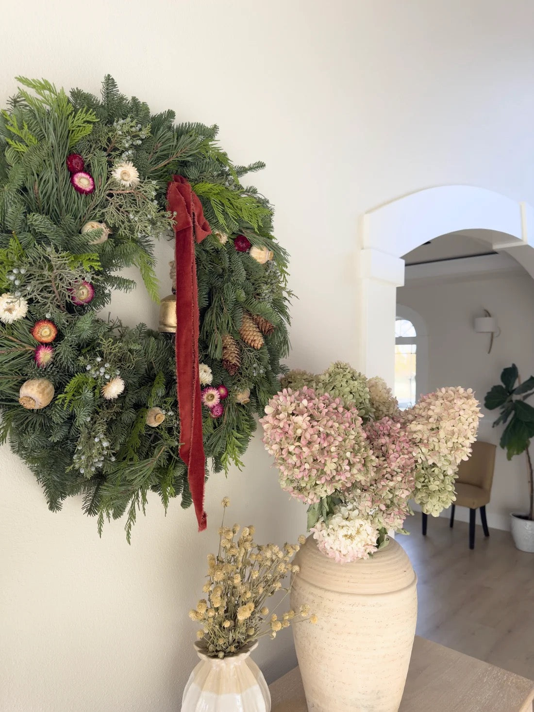 Juliette natural Christmas wreath beside a hydrangea arrangement in a ceramic vase

