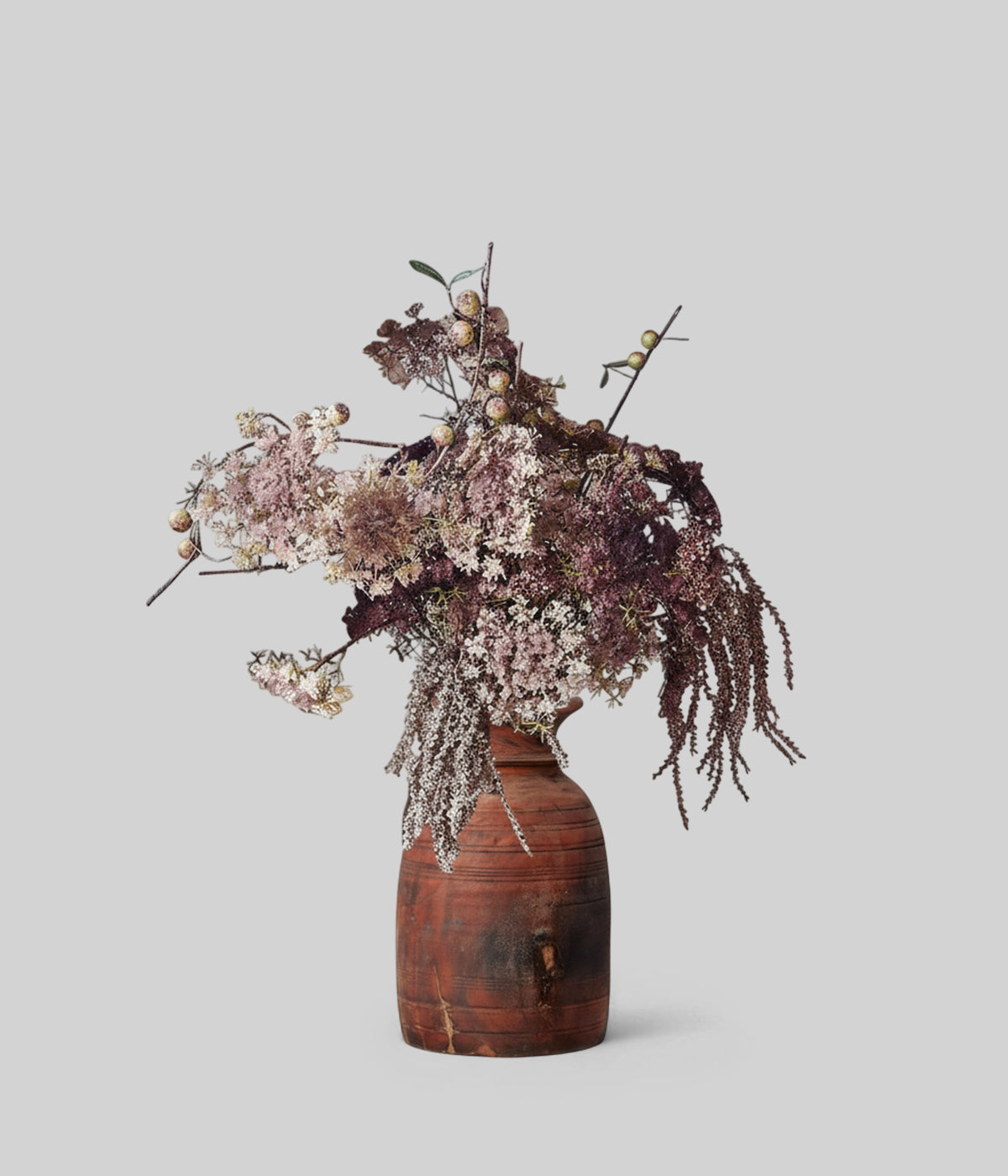 Blush and purple artificial flowers in a tall wooden vase