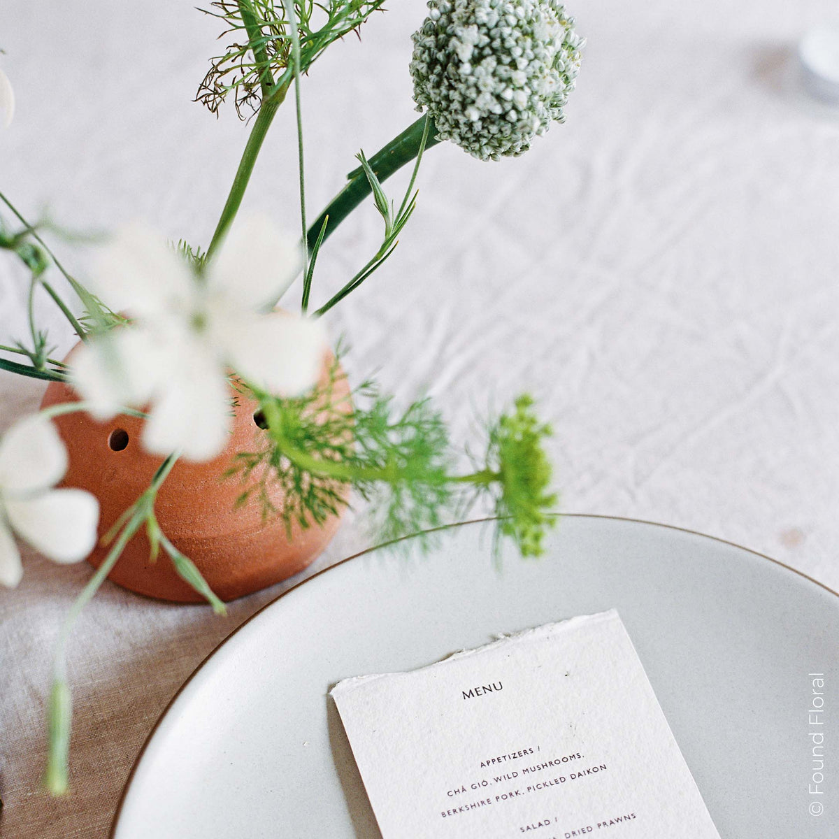 Frog vase with fresh stems on a formal table setting