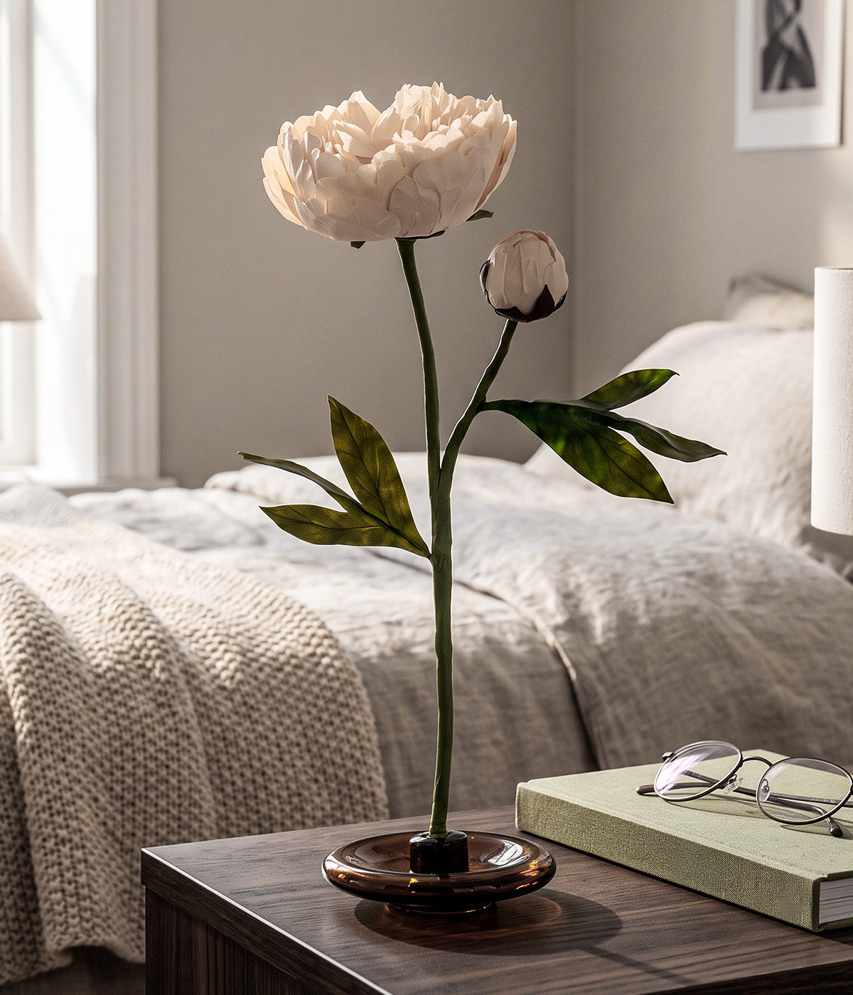 White paper peony displayed on a bedside table with its mouth-blown glass stand