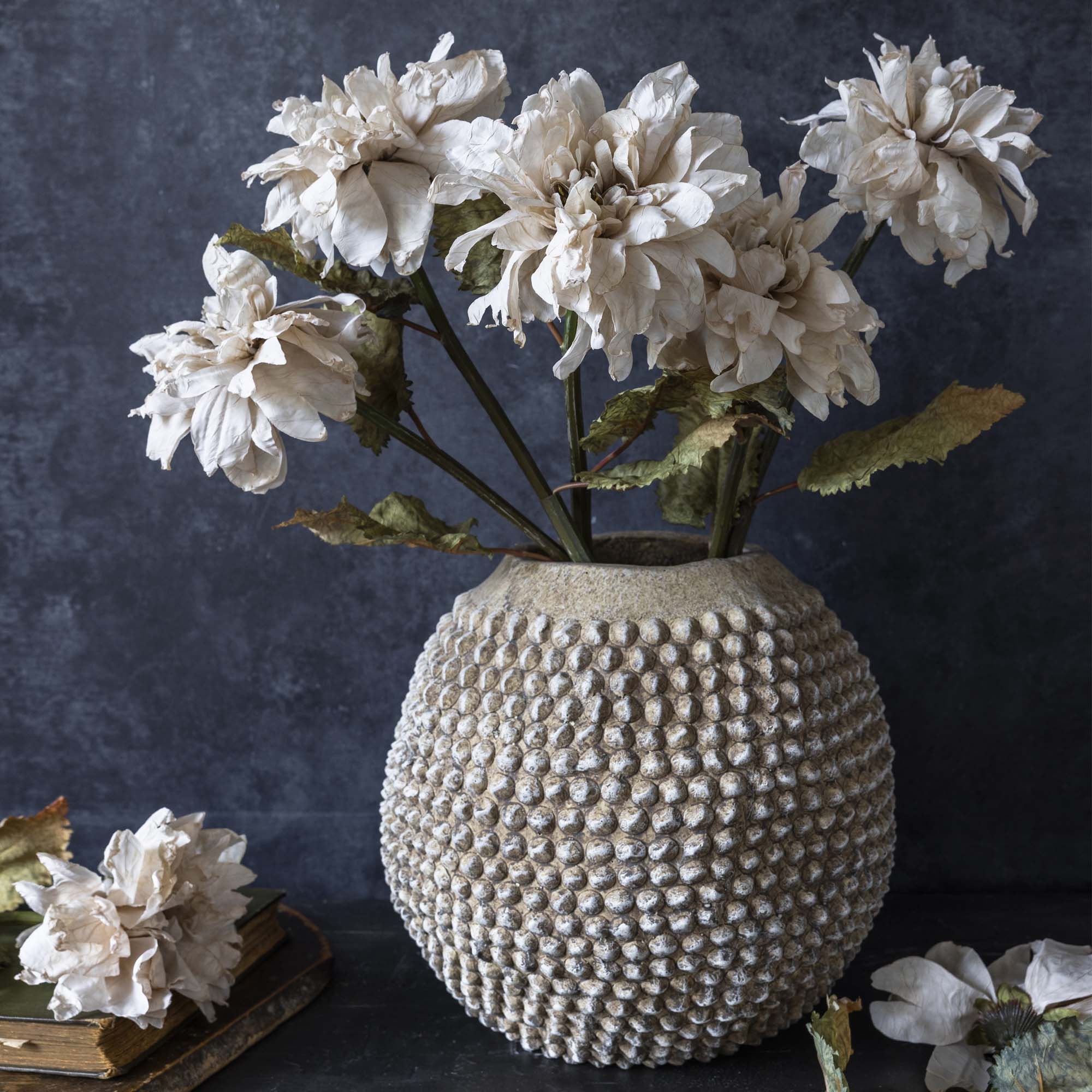 Artificial dahlia flower arranged in a textured stone vase