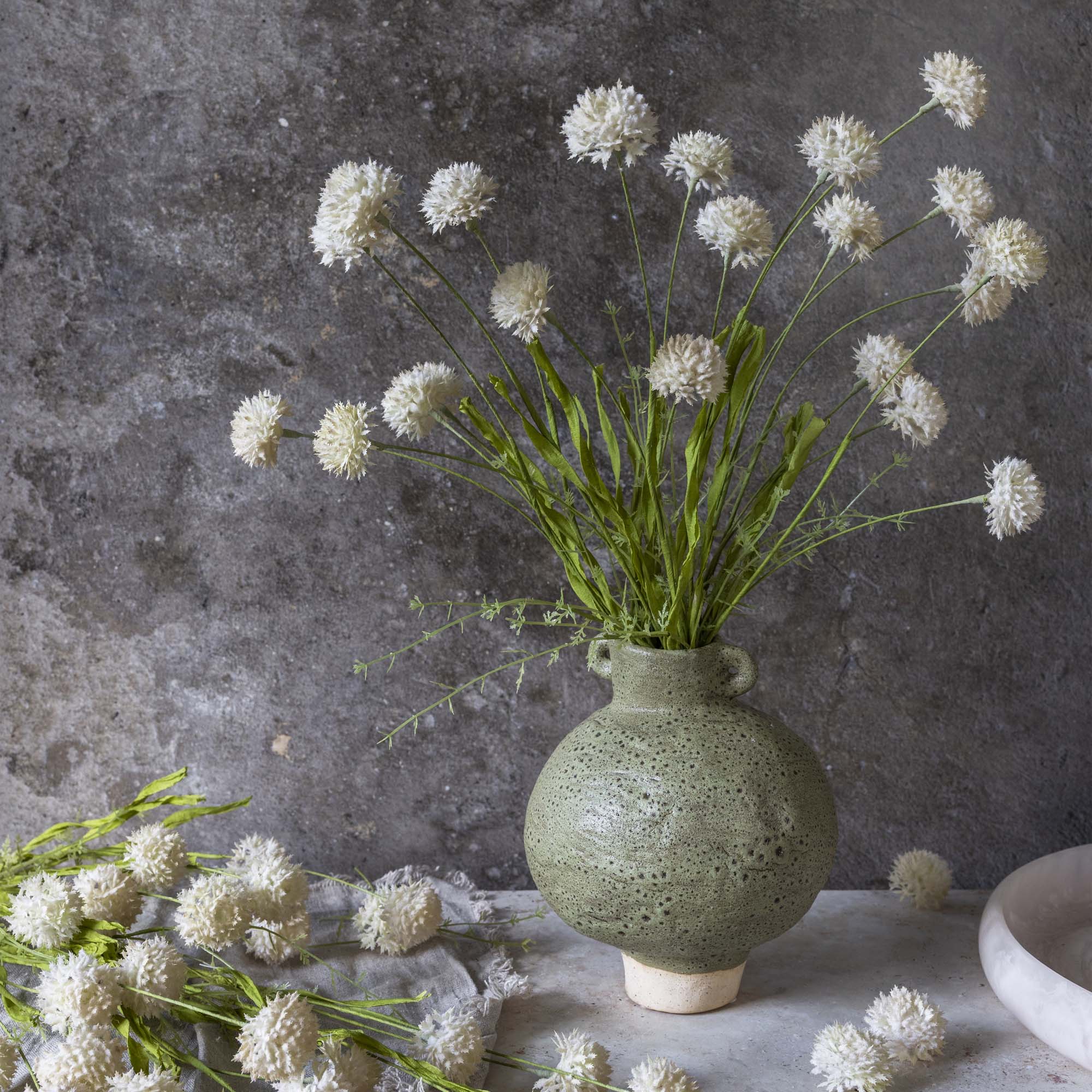 Faux Melaleuca, Cream – Large faux stem with softly spiky cream flower heads displayed in a stone vase.