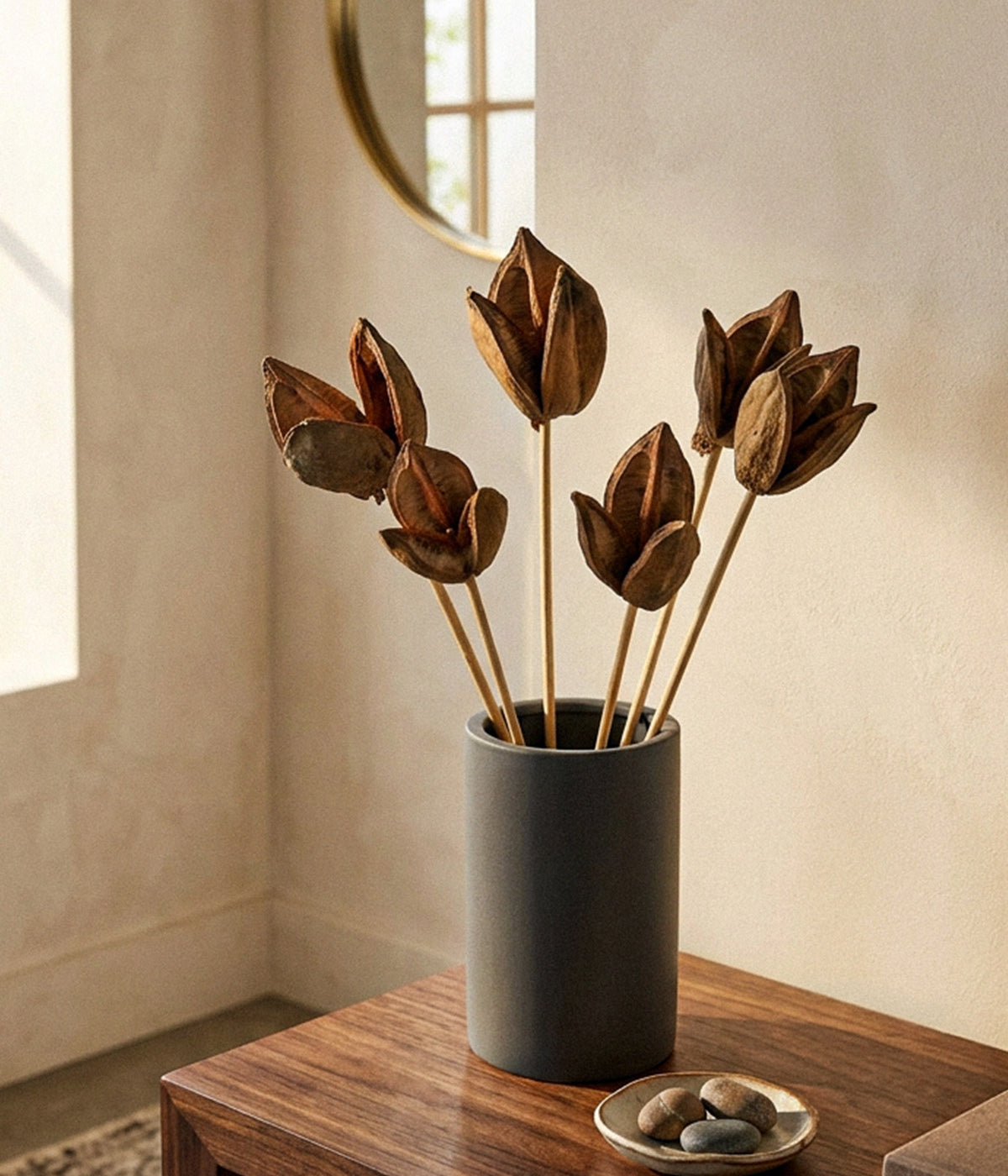Dried sora pod stems arranged in a dark cylindrical vase