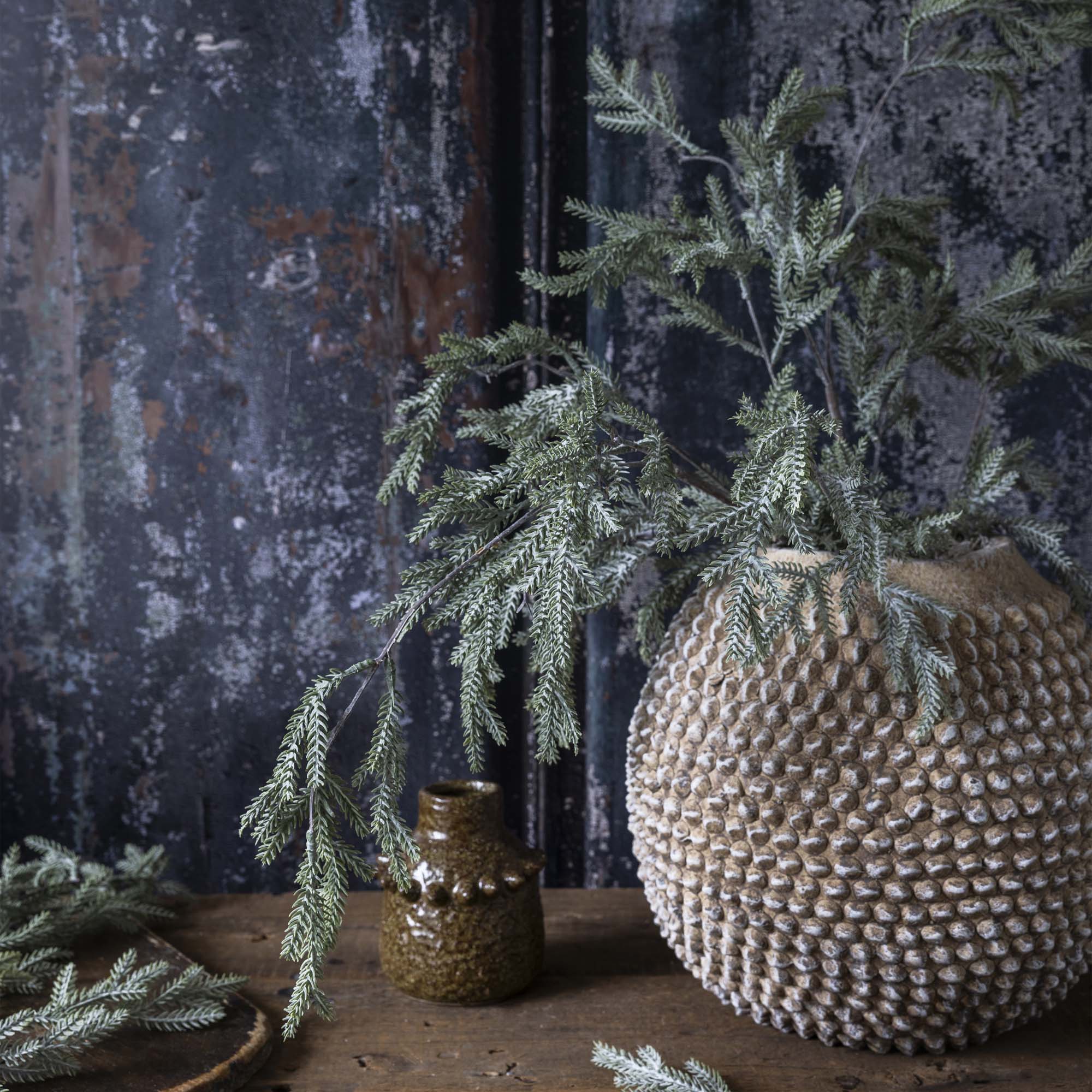 Frosted faux pine branch with natural form and muted tones for interior winter displays