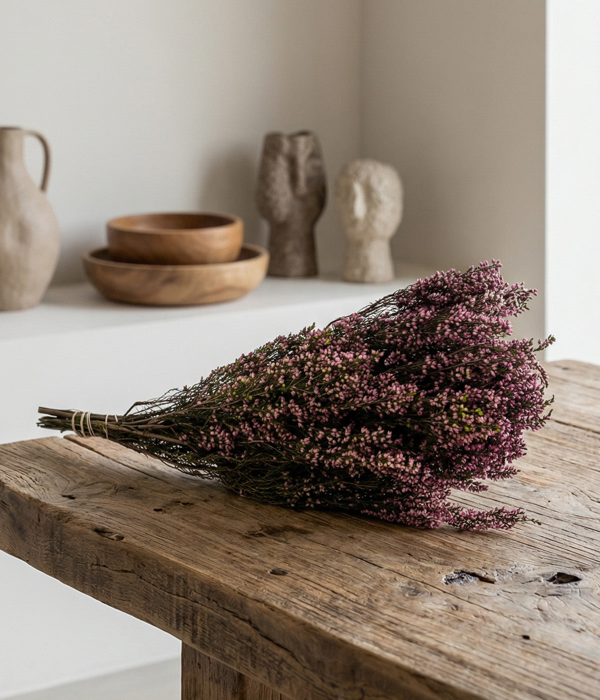 Preserved pink heather bundle displayed on rustic wood table with neutral decor